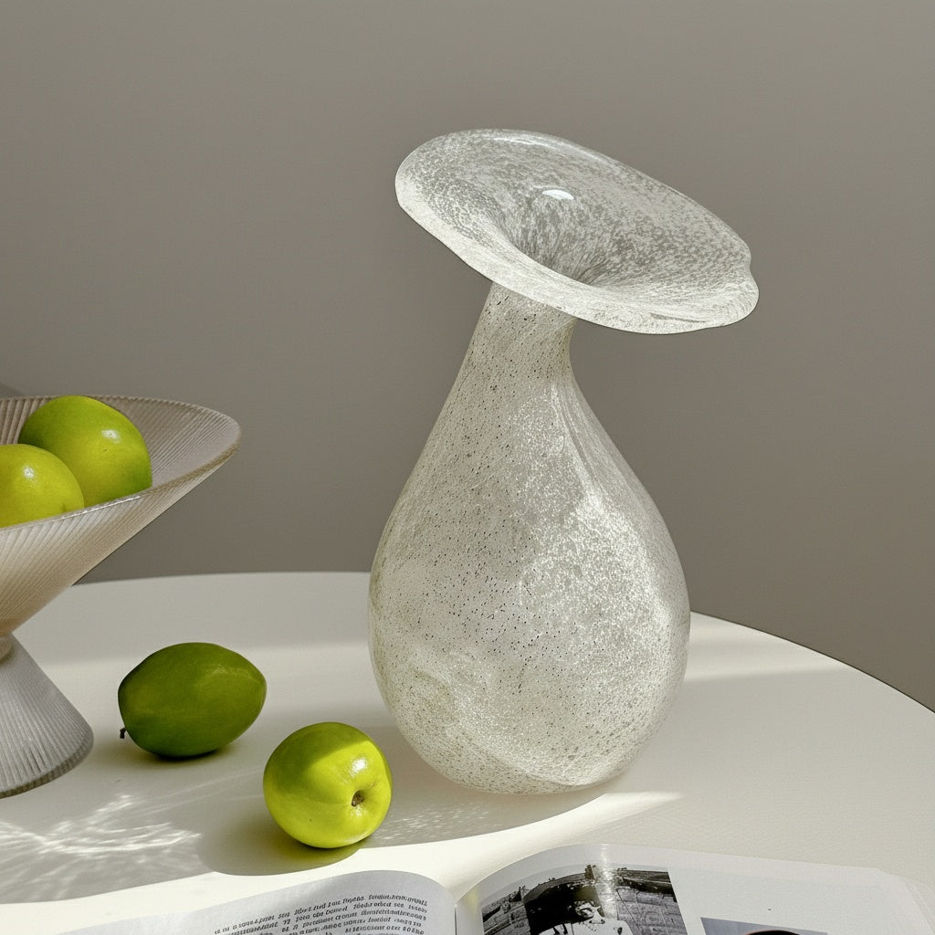 Angled view of white speckled glass vase with flared rim on table with green apples