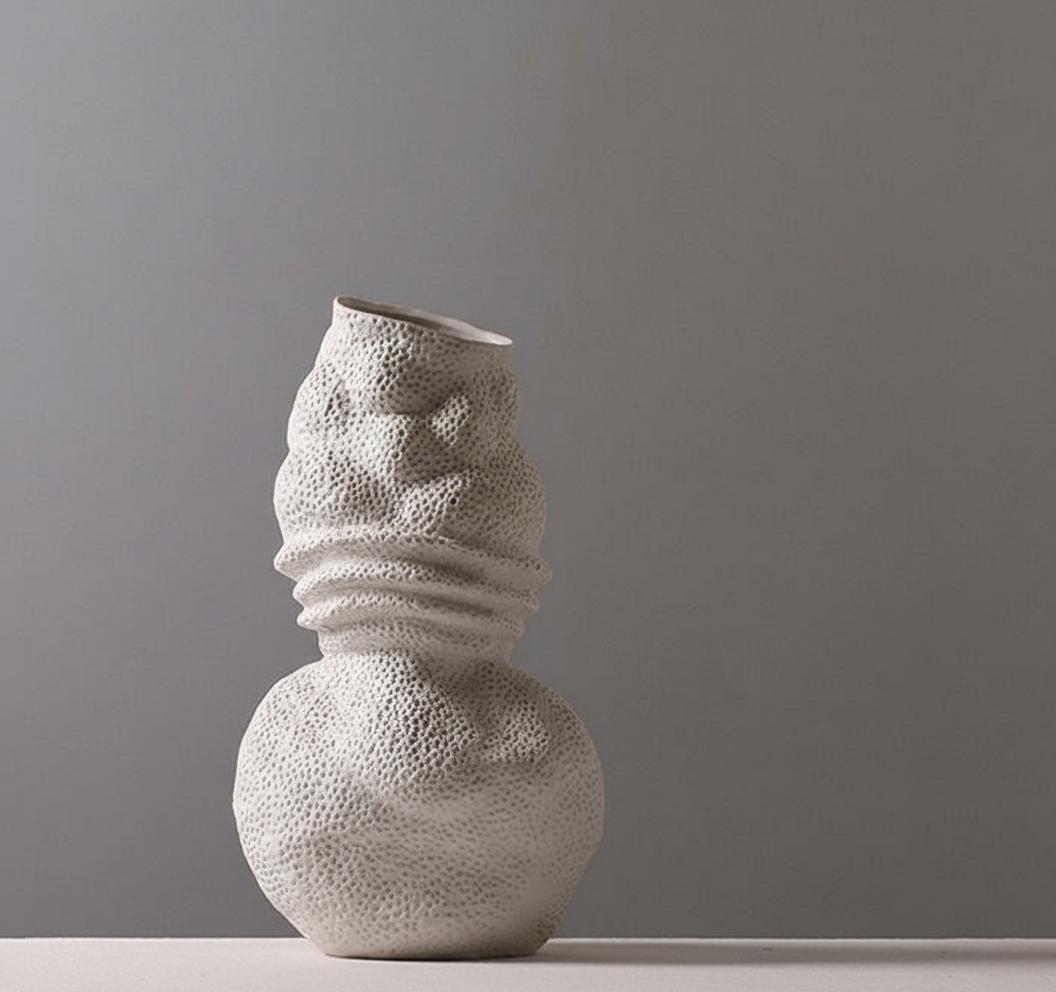 Side view of sculptural white vase