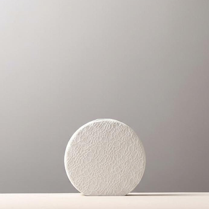 Close up detail of lace texture on white ceramic vase
