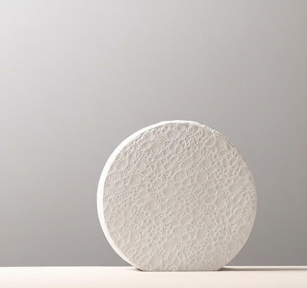 Angled view of round white ceramic vase showing texture