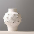 Angled view of round white ceramic vase