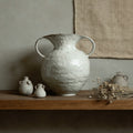 White textured ceramic vase styled on wooden shelf with dried flowers