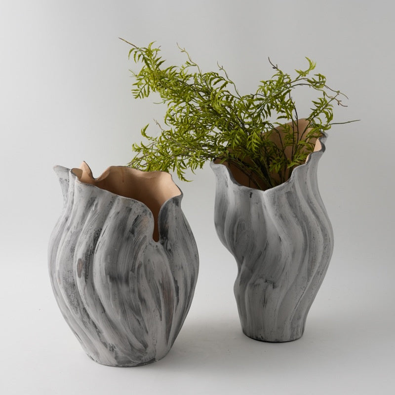 Two whitewashed grey ceramic twisted vases with greenery