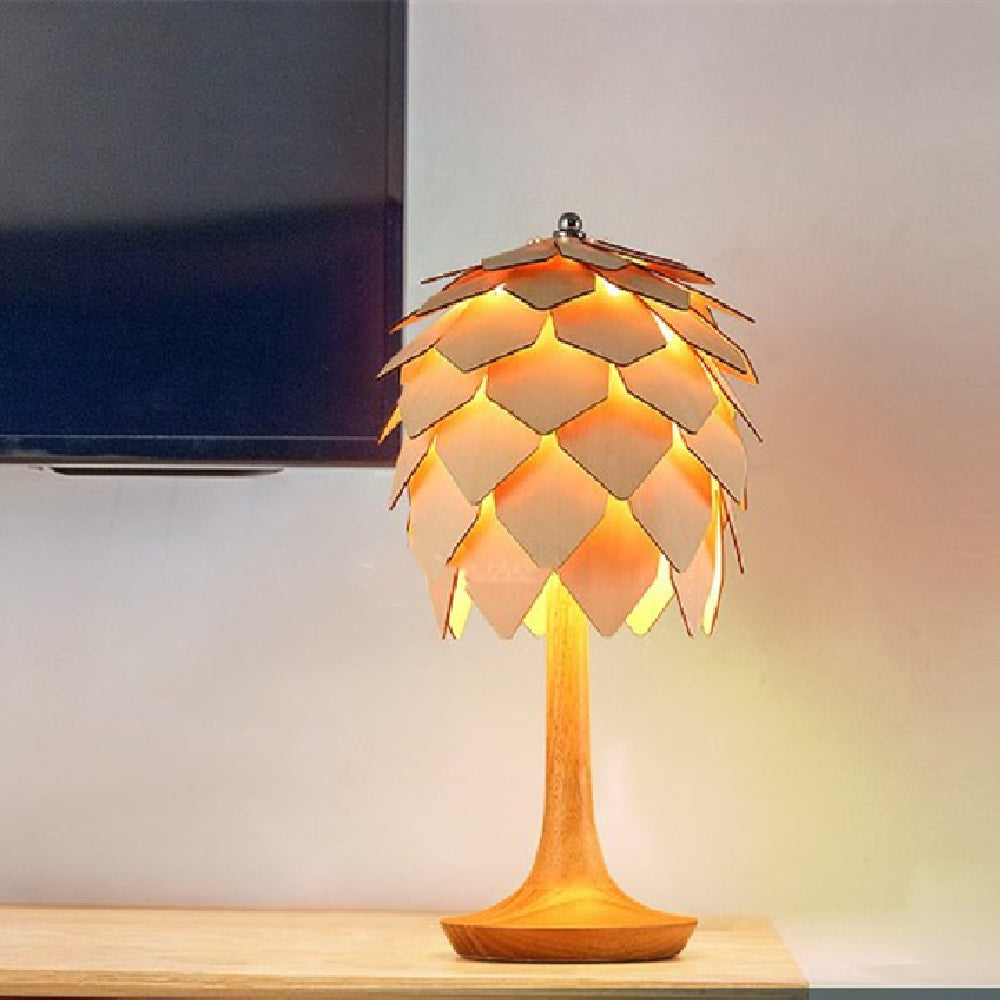Wood finish pinecone lamp on desk next to television