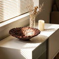 Top view of brown interlaced decorative bowl on white cabinet