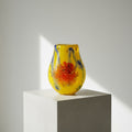 Close up of heavy yellow glass vase with red floral pattern