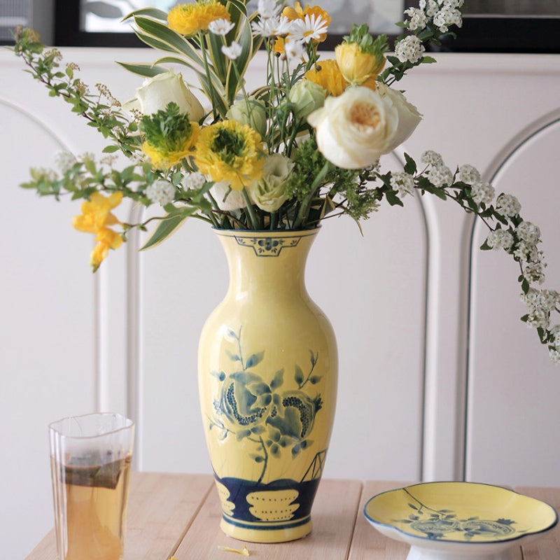 Lifestyle shot of yellow ceramic vase with flowers on wooden table