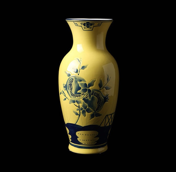 Studio shot of yellow and blue ceramic pomegranate vase on black background