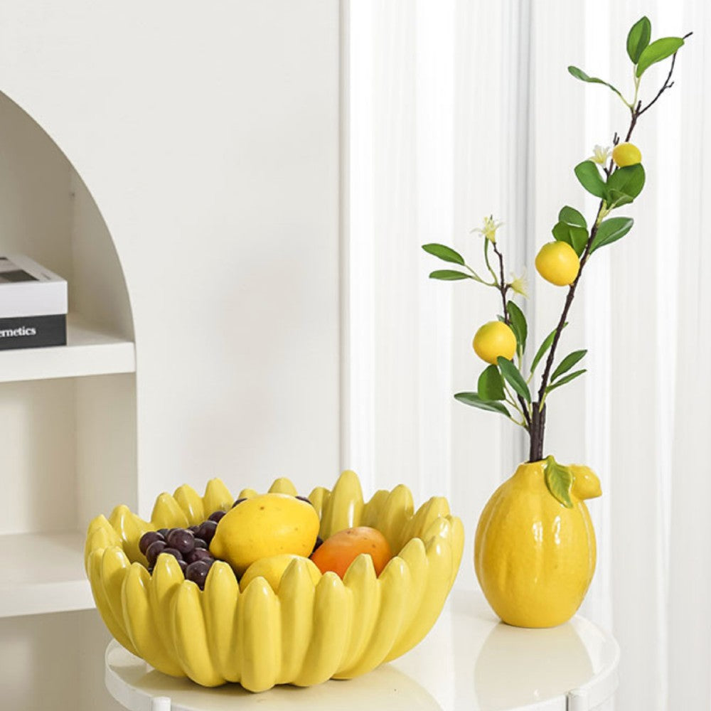 Yellow fruit bowl styled with lemons and grapes next to decorative vase