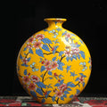Front view of yellow ceramic moon flask vase with floral and butterfly patterns