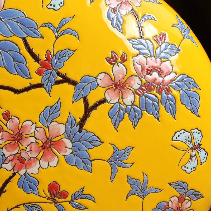 Close up detail of hand painted floral and butterfly glaze on yellow ceramic