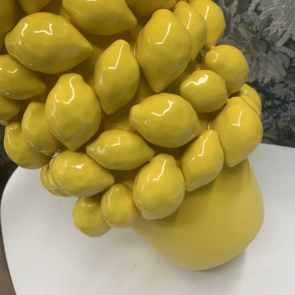 Close up of glossy yellow ceramic lemon vase with raised sculptural fruit texture
