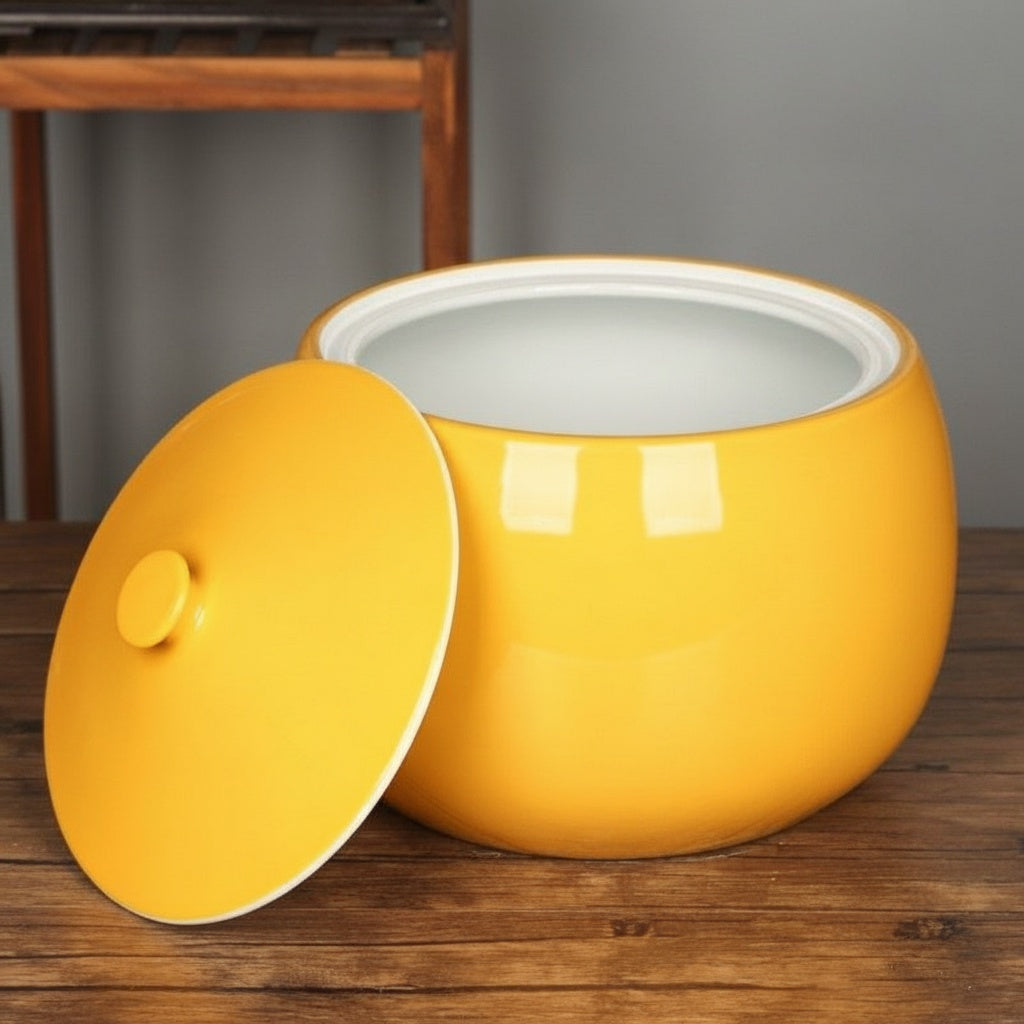 Yellow ceramic serving bowl with lid resting beside it showing white interior