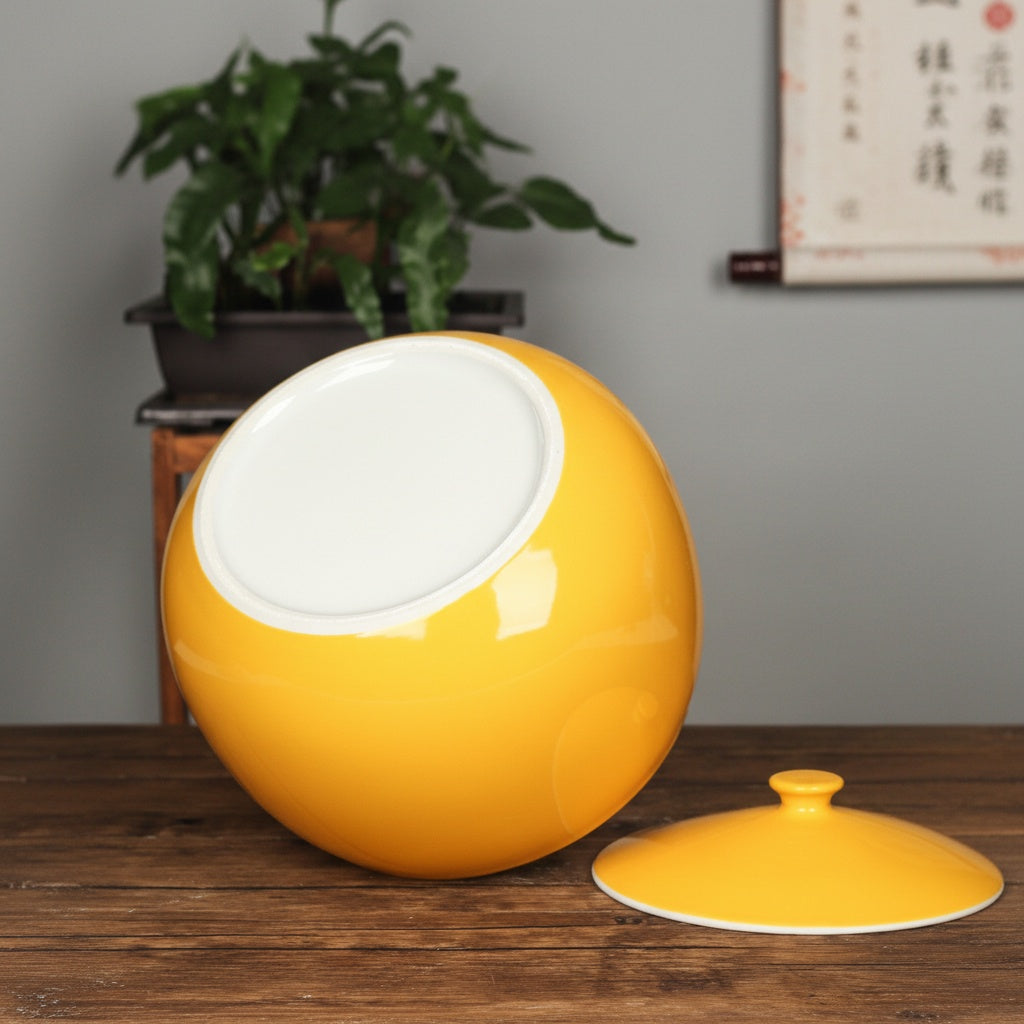 Underside of yellow ceramic bowl showing white base and matching lid