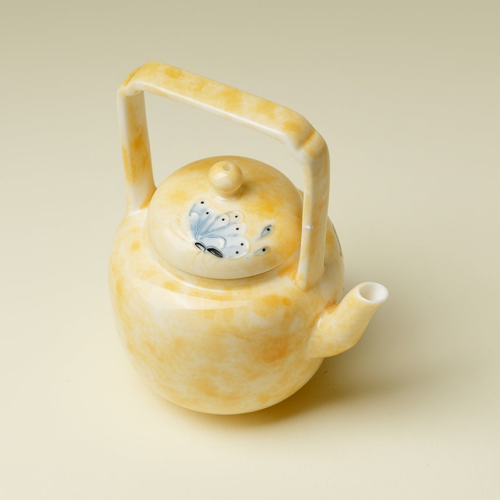 Top view of yellow porcelain teapot with butterfly lid