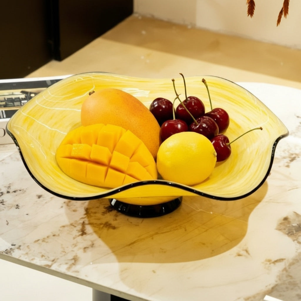 Yellow art glass bowl filled with fruit on table