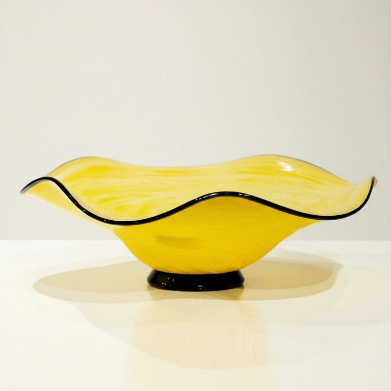 Studio shot of yellow pedestal bowl with black rim
