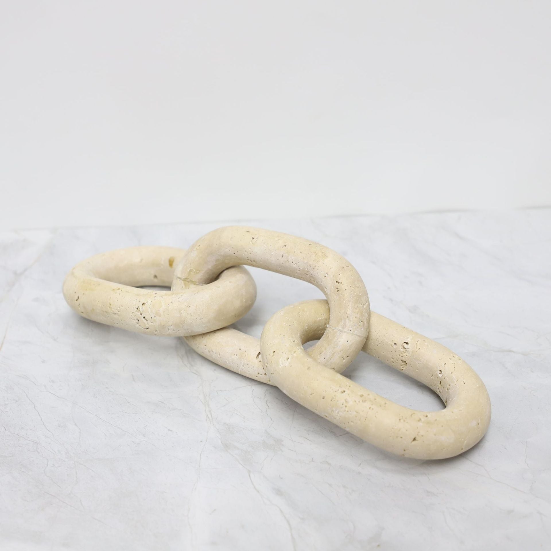 Angled side view of three-link stone chain sculpture